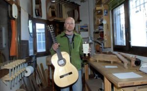 Sergio Valverde en su taller de Mecina Bombarón mostrando la guitarra clásica ganadora del certamen y la medalla de oro que recibió en Granada capital.